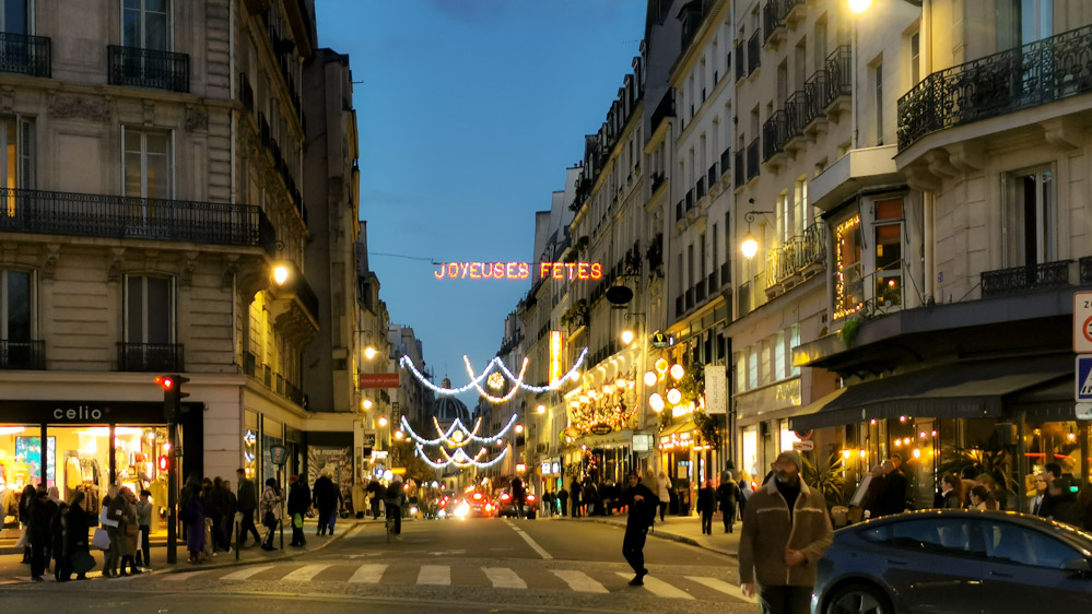 パリ、オデオン地区のクリスマスシーズンの様子。イルミネーションとオレンジの灯りが優しく包み込む。