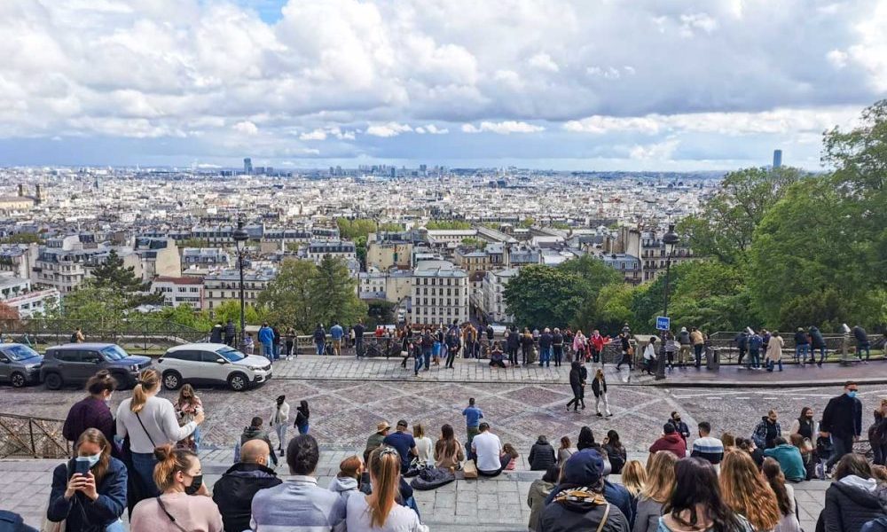 モンマルトルの丘からのパリの眺め。遠くのモニュメントまでよく見える。階段に座って景色を楽しむ若者。