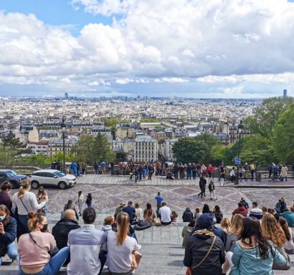 モンマルトルの丘からのパリの眺め。遠くのモニュメントまでよく見える。階段に座って景色を楽しむ若者。