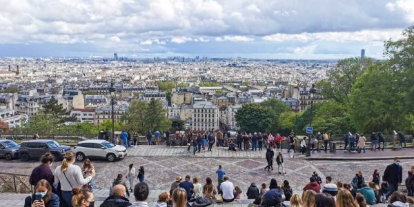 モンマルトルの丘からのパリの眺め。遠くのモニュメントまでよく見える。階段に座って景色を楽しむ若者。