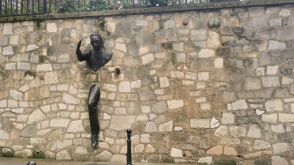 モンマルトルにある「壁抜け男」の銅像。壁から上半身と片足だけが飛び出ており、まさに壁を通り抜ける瞬間の姿が捉えられている。